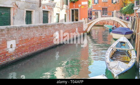 Den kleinen Kanal mit der kleinen Brücke gibt es einige Boote auf der Seite des Kanals und einige Leute über die Brücke in Venedig Italien Stockfoto