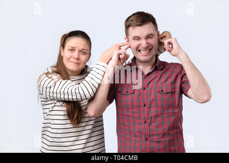 Frau ihren Ehemann Ohren schließen. Sie will etwas in geheim zu halten. Stockfoto