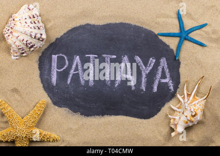 Handschriftliche Wort PATTAYA mit Kreide geschrieben, unter Muscheln und Seesterne. Ansicht von oben Stockfoto