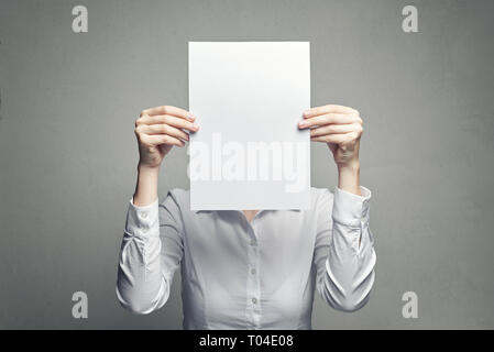 Anonyme business Frau in weißer Bluse mit Gesicht mit weißem Blatt Papier Stockfoto