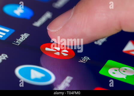 Finger drücken der Yelp App Symbol auf einem Tablet-PC oder Handy Touchscreen. Yelp Verknüpfung. Stockfoto