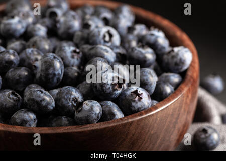 Nahaufnahme von frischen Heidelbeeren in eine hölzerne Schüssel auf einem dunkelgrauen Hintergrund Stockfoto