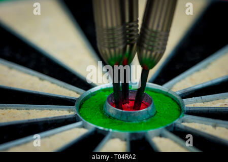 Macroshot von drei Darts in der Bulls Eye einer Dartscheibe Stockfoto