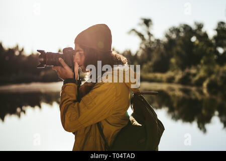 Tourist, ein Foto mit einer DSLR-Kamera. Seitenansicht eines Reisenden in seine digitale Kamera schauen, um ein Foto zu machen. Stockfoto