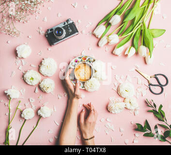 Weibliche Hände halten Kaffee, frischen Blumen und Kamera Stockfoto