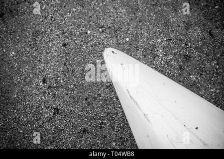 Kajak aus weißem Fiberglas Kunststoff mit im Alter von Marken mit weißen Kordel am Strand mit schwarzem Sand und Steine am Meer mit keine Menschen, Hintergrund Stockfoto