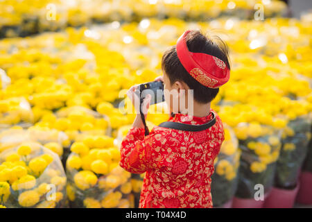 Kind mit digitalen Kompaktkamera im Freien. Süße kleine vietnamesische Jungen in Ao Dai Kleid. Tet holiday Stockfoto