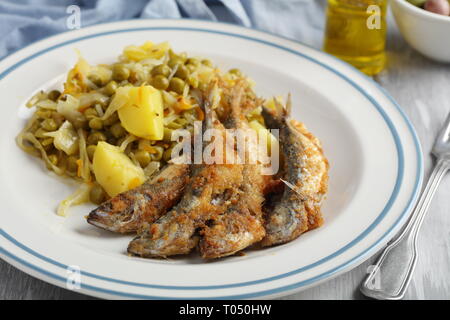 Chicharros fritos, traditionelle Portugal gebratene panierte Stöcker Fische mit Kohl, Kartoffeln und Erbsen Eintopf Stockfoto