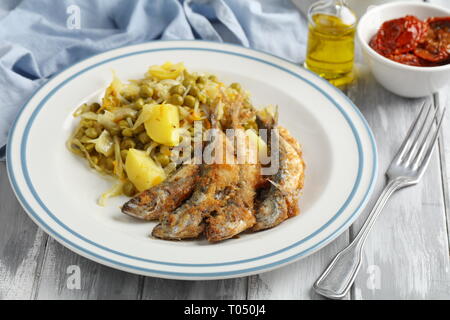 Chicharros fritos, traditionelle Portugal gebratene panierte Stöcker Fische mit Kohl, Kartoffeln und Erbsen Eintopf Stockfoto