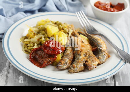 Chicharros fritos, traditionelle Portugal gebratene panierte Stöcker Fische mit Kohl, Kartoffeln und Erbsen Eintopf Stockfoto