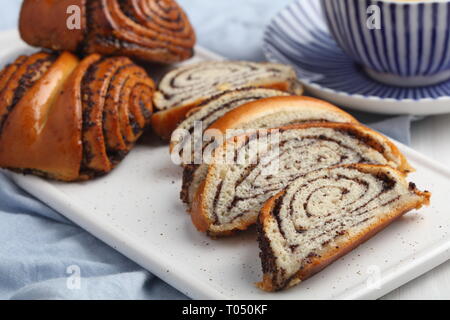 In Scheiben geschnitten und ganze Mohn Brötchen und einer Tasse grüner Tee Stockfoto