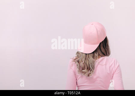 Blonde Frau in Rosa t-shirt und rosa Kappe auf hellen Hintergrund. Weiblichkeit und Feder. kopieren. Stockfoto