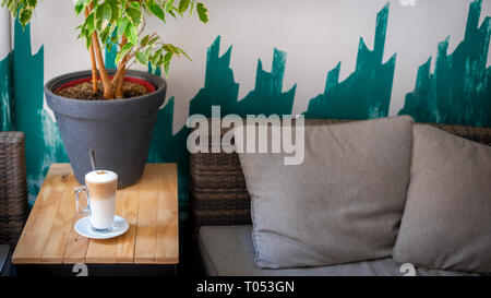 Lecker Café latte im hohen Glas auf einem Tisch in der Cafeteria oder Bistro. Milch Kaffee lifestyle Hintergrund mit kopieren. Kaffeepause Konzept. Stockfoto