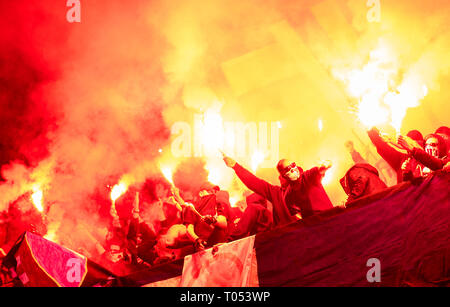 Fußball-Hooligans mit Maske halten Fackeln in Feuer, während Ihre Lieblingsmannschaft Unterstützung bei einem Spiel im Stadion Stockfoto