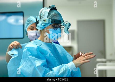 Chirurgen Verschleiß sterile Kleidung vor der Operation. Ein Team von Chirurgen Vorbereitung für die Chirurgie, die weiteres Licht auf den Kopf. Stockfoto
