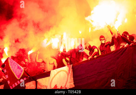 Fußball-Hooligans mit Maske halten Fackeln in Feuer, während Ihre Lieblingsmannschaft Unterstützung bei einem Spiel im Stadion Stockfoto