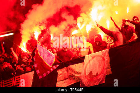 Fußball-Hooligans mit Maske halten Fackeln in Feuer, während Ihre Lieblingsmannschaft Unterstützung bei einem Spiel im Stadion Stockfoto