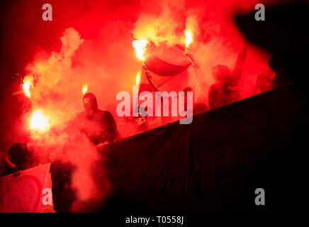 Fußball-Hooligans mit Maske halten Fackeln in Feuer, während Ihre Lieblingsmannschaft Unterstützung bei einem Spiel im Stadion Stockfoto