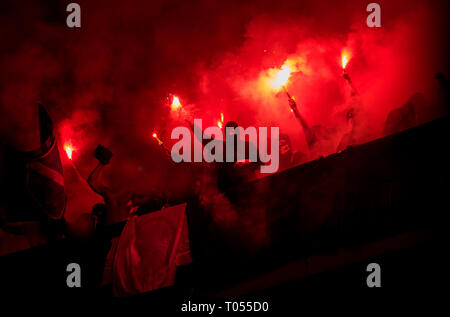 Fußball-Hooligans mit Maske halten Fackeln in Feuer, während Ihre Lieblingsmannschaft Unterstützung bei einem Spiel im Stadion Stockfoto
