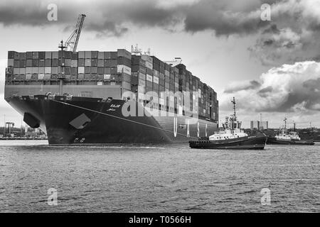 Schwarz/Weiß-Bild von drei Schleppern Unterstützung Der uasc Ultra-Large Container schiff, SAJIR, Abfahrt der Southampton Container Terminal, Hampshire, UK. Stockfoto