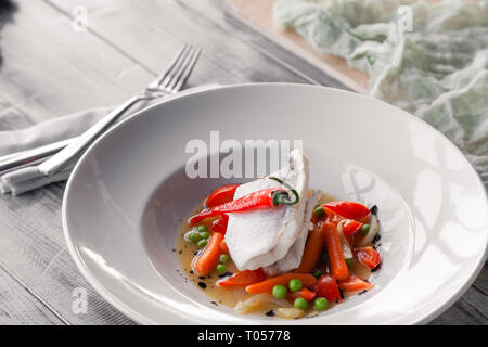 Closeup Filet gedünsteten Zander mit Gemüse, Chili, Tomaten, Zwiebeln, mini Karotten mit Soße auf den Tisch im Restaurant serviert. Konzept professi Stockfoto