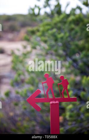 Rote metall Schild mit einer Silhouette von zwei Wanderer auf den Wanderweg zu einem Wanderweg in der Nähe von Blanding, Utah zeigt auf einem unscharfen Hintergrund der Bäume. Stockfoto