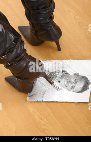 Eine junge Frau zerquetscht ein Foto von ihr Partner mit Ihrer Ferse. Das Glas des Bilderrahmens ist erschüttert. Stockfoto