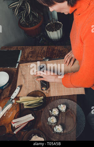 Eine Frau Koch bereitet Sushi in der Küche und wickelt einen Brief an die Nori in der Rolle 2019 Stockfoto