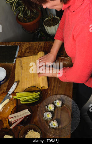 Eine Frau Koch bereitet Sushi in der Küche und wickelt einen Brief an die Nori in der Rolle 2019 Stockfoto