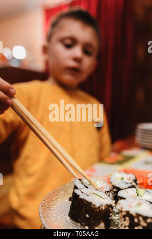 Die jugendlich Junge nimmt das Sushi Roll der Platte 2019 Essen Stockfoto