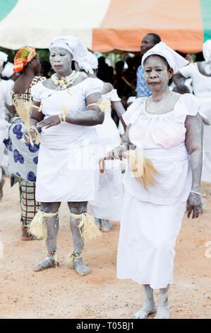Adzopé, Elfenbeinküste - 31. August 2016: Zwei junge Frauen in weißes Pulver auf den Körper mit Ketten gekleidet, ohne pferdeschwanz Schuhe in der Hand vorbereiten Stockfoto