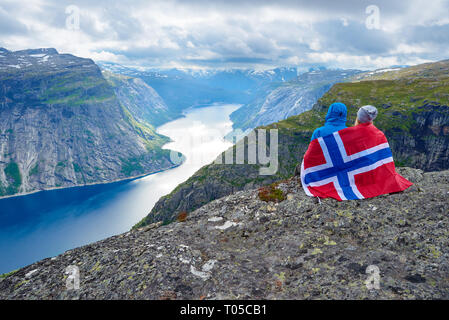 Paar sitzt auf Felsen und blickt auf die Berge in der Nähe von trolltunga. Beliebte Touristenattraktion. Ringedalsvatnet - See in der Gemeinde Odda in Hordalan Stockfoto