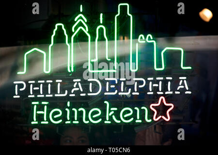Werbung mit einem stilisierten Teil der Skyline der Stadt für Heineken im Fenster eines lokalen Bar im Zentrum der Stadt Philadelphia, PA am 15. März 2019. Stockfoto