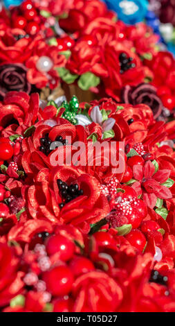Zusammensetzung der kleinen handgemachten Blumen, rot und Bordeaux Rosen, Perlen, grüne Blätter Stockfoto
