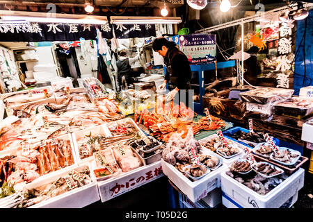 Tokyo, Japan - 15. Januar 2010: am frühen Morgen in Tsukiji Fischmarkt. Arbeitnehmer Festlegung aus frischem Fisch und Meeresfrüchten auf den Tresen. Stockfoto