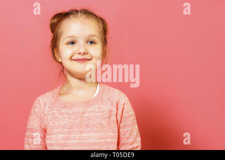 Closeup Portrait von niedlichen kleinen Kind Mädchen mit Brötchen von Haar über rosa Hintergrund Stockfoto