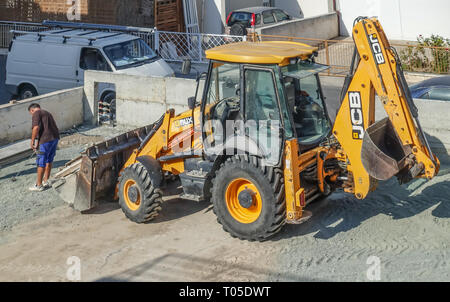 Limassol, Zypern - 4. November 2018: Die Große gelbe JCB Traktor auf einer Baustelle. Fahrzeug ist groß im Rahmen. Mann mit Maßband vor. Stockfoto