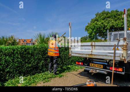 Eastbourne, Sussex, England, Großbritannien - 1 August 2018: Workmanj Harken der Garnituren eines neu Schnittkante. Das Tragen eines Hi-viz jacketand Backend von Lastwagen. Stockfoto