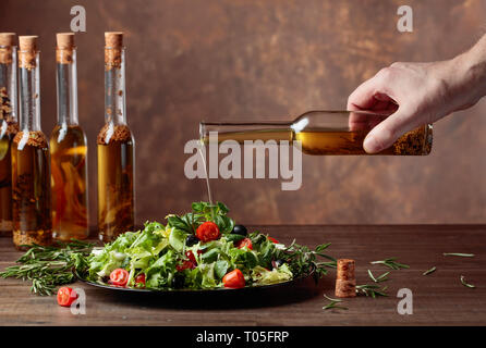 Salat mit Olivenöl Gießen von einer kleinen Flasche. Kopieren Sie Platz. Stockfoto