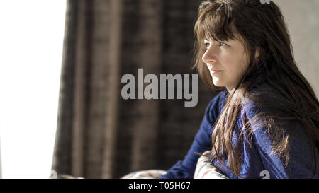 Hübsche brünette Frau lächelnd sitzen in ihrem Bett am Morgen Stockfoto