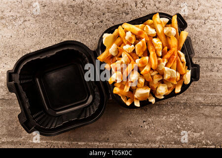 Poutine in einem takeout Container. Mit Pommes frites, Rindfleisch, Soße und Quark Käse gekocht. Kanadische Küche. Stockfoto