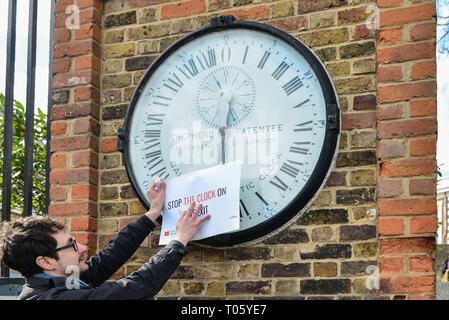 London, Großbritannien. 17 Mär, 2019. Aktivist Andreas Pisauro legt'S top Die Uhr auf Brexit' Schild Greenwich Wecker neben dem Greenwich Meridian line. Eine britische Druck Gruppe namens "Machen Sie eine Pause vom Brexit und Neue Europäer Irland Protest in Greenwich Park die Heimat von GMT. Eine nationale Kampagne, Gruppe, die gerne Brexit um mindestens ein Jahr verschoben. Credit: Claire Doherty/Alamy leben Nachrichten Stockfoto