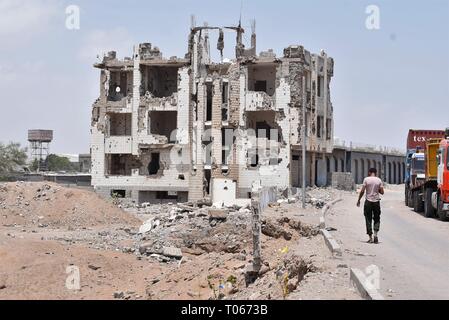 Aden, Jemen. 17 Mär, 2019. Ein Mann in der Nähe eines Gebäudes während der Kämpfe zwischen Regierungstruppen und den Rebellen Houthi in Aden, Jemen, am 17. März 2019 zerstört. Die interne militärische Konflikt zwischen der jemenitischen Regierung und der Rebellen Houthi weiterhin unter mangelnder politischer Lösungen für einen dauerhaften Frieden in den verarmten arabischen Land zu erreichen. Von Jemen Bürger haben gelitten, das auf vier Jahre verheerende Konflikt, Zehntausende von Toten oder Verletzten, darunter mindestens 17.700 Zivilisten, von den Vereinten Nationen überprüft. Credit: Murad Abdo/Xinhua/Alamy leben Nachrichten Stockfoto