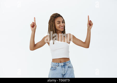 Mädchen hinting wir ehrfürchtige Sache nach oben sehen können. Erfreut und glücklich zuversichtlich afrikanische amerikanische Junge weibliche mit Dreadlocks freudig lächelnd anheben Stockfoto