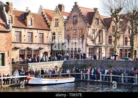 Brügge, Belgien - 17. FEBRUAR 2019: Stadt Canal, viele Touristen. Ausflugsboote am Pier Stockfoto