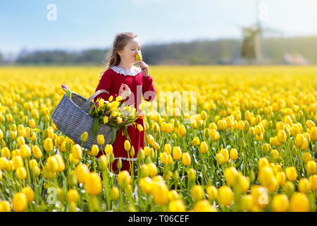 Kind in gelbe Tulpe Blume Bereich. Blühender Garten in Holland, Niederlande. Kleines Mädchen in Tulpen Farm. Kind mit Korb Kommissionierung frische Blumen auf Sunn Stockfoto