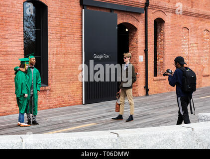 CHARLOTTE, NC, USA -3/16/19: Junger Mann und Frau haben ihre Bilder aufgenommen, die Graduierung tragen Kleider, vor Gpogle Fibre Gebäude. Stockfoto