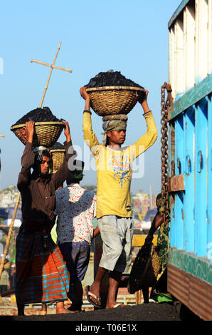 Bangladeshi arbeit Kohle, die ihre Köpfe von den Schiffen zu den Lastwagen. Stockfoto