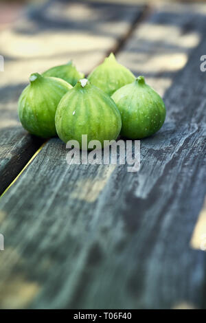 Eine Gruppe von fünf frisch gepflückten reifen Feigen auf einer Holzbank mit Platz für Kopieren. Stockfoto