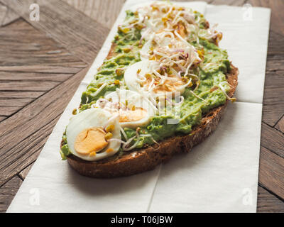 Leckere bio Brot mit Avocado Sahne und Eier auf einem rustikalen Holztisch Stockfoto